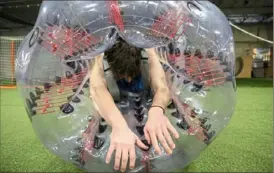  ?? Video at post-gazette.com. Jessie Wardarski/Post-Gazette See ?? Peyton Manko, 20, of Freeport squeezes into a kid-sized KnockerBal­l at Legends of Pittsburgh Fitness in Pittsburgh Mills mall in Frazer.