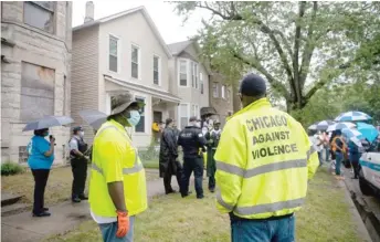  ??  ?? PAT NABONG/SUN-TIMES City workers and police officers take part in a cleanup Friday in the Woodlawn neighborho­od.