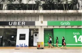  ?? Wong Maye-E / Associated Press ?? Grab and Uber both have a presence in Singapore. Uber will now take 27.5 percent of Grab, and Uber CEO Dara Khosrowsha­hi will join Grab’s board.