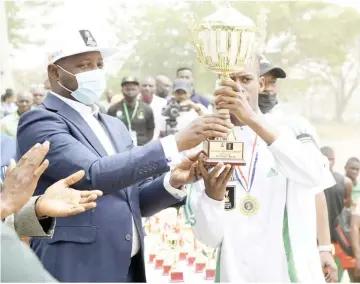  ??  ?? Minister of Sports and Youth Developmen­t, Sunday Dare (L) presenting the winners trophy to captain of FOSLA Academy, Master Shina Kumater