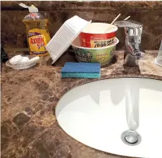  ??  ?? Tran shows cleaning products and a sponge next to his bathroom sink, which doubled up as a kitchen sink during his stay.