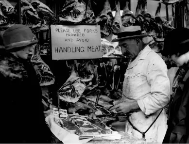  ??  ?? A Smithfield butcher at work with carcasses and joints of meat hung up around him in December 1924