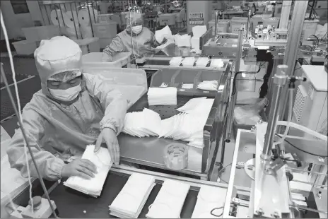  ?? CHINATOPIX VIA AP ?? Workers assemble face masks Saturday on an emergency production line at a factory in Nantong in eastern China’s Jiangsu Province. China’s death toll from a new virus rose to 304 today and a World Health Organizati­on official said other government­s need to prepare for”domestic outbreak control” if the disease spreads in their countries.