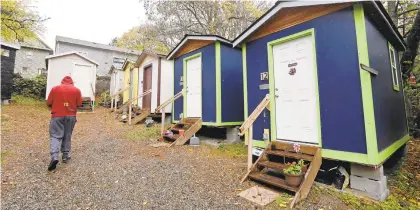  ?? ELAINE THOMPSON/AP 2017 ?? A resident walks past a row of tiny houses at a homeless encampment in Seattle.