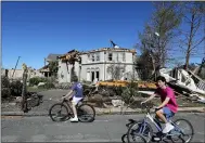  ?? LM OTERO — THE ASSOCIATED PRESS ?? Bicyclists ride past a house damaged by a tornado in the Preston Hollow section of Dallas, Monday.