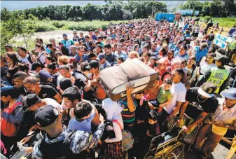  ?? Schneyder Mendoza / AFP / Getty Images ?? People line up to cross a bridge from San Antonio del Tachira in Venezuela to Cucuta in Colombia to buy goods that are unattainab­le in Venezuela because of widespread shortages.