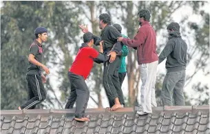  ?? AP ?? Asylum seekers stop a fellow detainee from jumping off the Villawood Detention Centre roof in Sydney, Australia, during a protest by the detainees who say they are scared of being returned to their home countries.