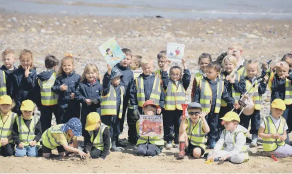  ?? ?? Children holding up two of the books they had read before taking part in the beach clean.