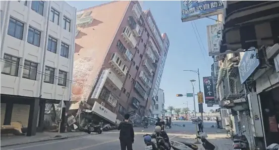  ?? TVBS ?? Residents stare at a partially collapsed building in Hualien after a powerful earthquake rocked the island of Taiwan early yesterday.
