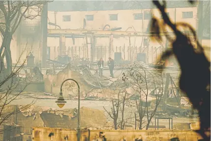  ?? John Locher, The Associated Press ?? News reporters stand Tuesday in an area burned by a wildfire in Paradise, Calif. An additional 150 search-and-rescue personnel are looking for remains in a blaze that has killed at least 48 people.