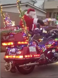  ??  ?? Bill Clift, aka Moto Santa, mounts his motorcycle for a ride around town.