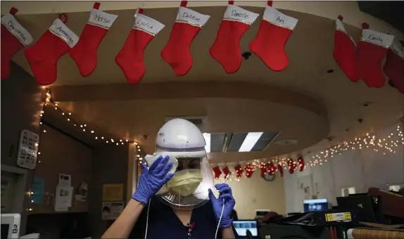  ?? JAE C. HONG — THE ASSOCIATED PRESS ?? Registered nurse Romina Pacheco disinfects her powered air purifying respirator after tending to a patient in a COVID-19 unit decorated with Christmas stockings with nurses’ names written on them at Mission Hospital in Mission Viejo, Calif.