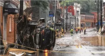  ?? Libby Solomon / Baltimore Sun ?? Rescue workers make safety checks along the historic Main Street in Ellicott City, Md., Sunday.