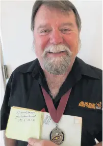  ?? PHOTO: SUPPLIED ?? Eddy Garner proudly displays his Burt Munro's mementoes: a book with the Fastest Indian's signature and a medal from the 2018 challenge.