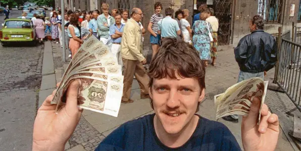  ?? Foto: Kai-Uwe Wärner, dpa ?? Der 1. Juli 1990 war ein historisch­er Tag für Deutschlan­d: Nach langem Schlangest­ehen vor einer Leipziger Sparkassen-Filiale freut sich dieser Mann über seine D-Mark-Banknoten.