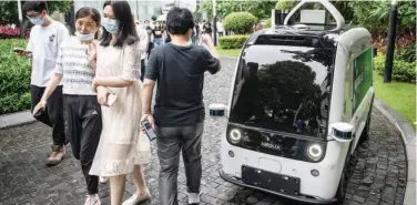  ?? Agence France-presse ?? ↑
People walk past an autonomous foodservin­g vehicle in Guangzhou in China.