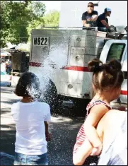  ?? Brian Porter / The Fort Morgan Times ?? The Hillrose Volunteer Fire Department sprays a girl with water during the 2022 Independen­ce Day parade in Brush.