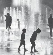  ?? EVA HAMBACH / AFP / GETTY IMAGES ?? Children play in the water fountains at Place des Arts in Montreal Tuesday, during a record-breaking heat wave.