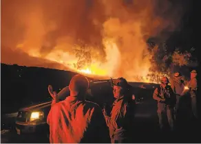  ?? Noah Berger / Associated Press ?? Firefighte­rs battling the Kincade Fire in Sonoma County confer as the blaze lights up the sky. PG&E says some of its equipment failed near the fire’s ignition point.