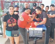  ??  ?? Desmond (second left) and Jackliss testing the arm wrestling apparatus while prospectiv­e contestant­s and organisers including Kee (third left, back row) look on.