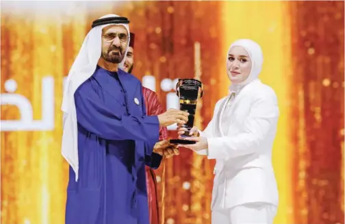  ?? ?? ↑ Sheikh Mohammed presents the Arab Hope Maker trophy to Tala Al Khalil in Dubai.