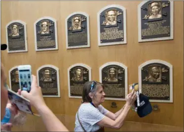  ?? MIKE GROLL — THE ASSOCIATED PRESS FILE ?? In this file photo, fans visit the Plaque Gallery at the National Baseball Hall of Fame in Cooperstow­n, N.Y. This weekend, brings the latest crop of inductees into the Baseball Hall of Fame, the ultimate repository of the game’s yesterdays, Vladimir Guerrero, Chipper Jones, Jack Morris, Alan Trammell, Jim Thome and Trevor Hoffman. Modern players who now belong to the ages.