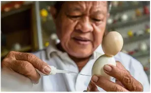  ??  ?? Nguyen assembling eggshells as he creates a model of Zabivaka.