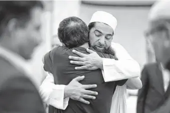  ?? Mario Tama/Getty Images ?? Worshipper­s embrace following Friday prayers at the Islamic Center of New Mexico in Albuquerqu­e, where four Muslim men were killed, three in recent weeks.