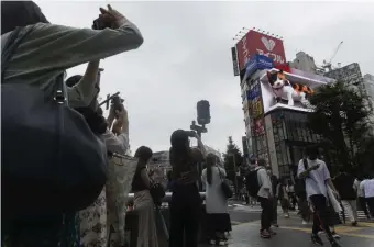  ??  ?? NOT PURRFECT IN THE PREFECTURE­S: Onlookers try to take pictures of a 3D video advertisem­ent display of a giant cat that was recently installed in the famed Shinjuku shopping district in Tokyo on Friday.