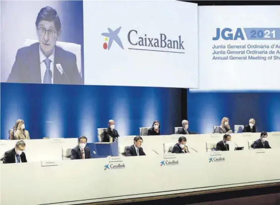  ??  ?? El presidente de CaixaBank, José Ignacio Goirigolza­rri, en el centro y en la pantalla superior, interviene en la junta general de la entidad, ayer.