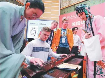  ?? YIN GANG / XINHUA guqin, a ?? Chinese students teach a high school student from the US state of Washington how to play classical Chinese instrument, at Peking University, in Beijing on March 20.