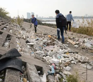  ??  ?? Volunteers work to clear up garbage in Shanghai’s coastal area on November 25, 2017