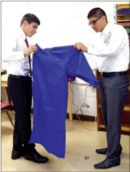  ?? Photo by Mike Eckels ?? Jafett Puga (left) held his gown open while Marck Guadarrama used a steam iron to smooth out the wrinkles prior to the 2017 Decatur High School graduation ceremony at Peterson Gym on May 14.