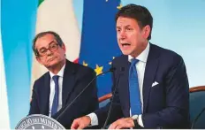  ?? AP ?? Italian minister of economy and finance Giovanni Tria (left) and Premier Giuseppe Conte at a conference in Rome Wednesday. Tria is backing down on spending plans.