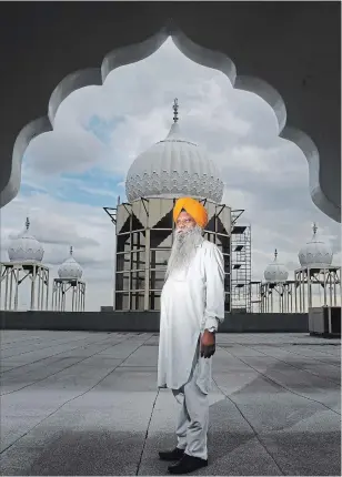  ??  ?? Sewa Singh, head priest of the Gurdwara Shaheedgar­h Sahib Hamilton, on the roof of Gurdwara Thursday with the newly installed domes in the background.