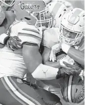  ?? WADE PAYNE/AP ?? UF linebacker David Reese II, front left, wraps up Tennessee running back Tim Jordan during a game last season. Reese is being counted on to anchor the linebackin­g corps.