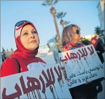  ?? THE ASSOCIATED PRESS ?? A woman holds a placard reading “No to Terrorism” as she demonstrat­es Thursday in front of the National Bardo Museum a day after gunmen attacked the museum and killed scores of people in Tunis, Tunisia.