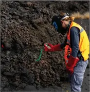  ?? (AP/Emilio Morenatti) ?? A scientist with the Canary Islands’ volcanolog­y institute, Involcan, measures the temperatur­e of a lava flow Oct. 30 Despite technologi­cal and scientific leaps, predicting volcanic eruptions and, more crucially, how they end, remains a mystery.