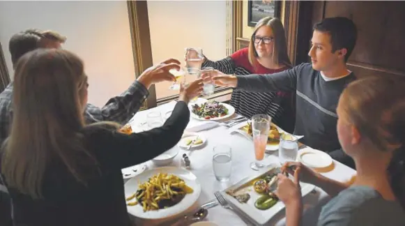  ?? Joe Amon, The Denver Post ?? University of Colorado junior Emily Murray, rear, and her date, Braedon Bellamy, 19, toast her 20th birthday with her foster family, Marcus and Jennifer Pennell, left, and their 12-year-old daughter, Amelia, at the Brasserie Ten Ten restaurant in Boulder last week.