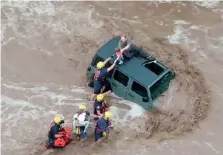  ?? GOLDER RANCH FIRE DISTRICT VIA AP ?? This drone image shows firefighte­rs safely rescue a man and his two daughters from the roof of their vehicle after it was swept away in fast moving water just north of Tucson, Ariz., on Wednesday.