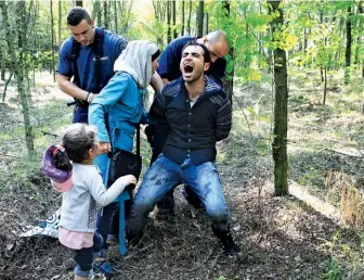  ??  ?? + BORDER FORCE: Hungarian police detain a Syrian family in August 2015 after they entered the country from Serbia.