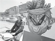  ?? AHN YOUNG-JOON, AP ?? A protester sits next to a poster depicting President Trump to oppose deploying an anti-missile system known as THAAD.