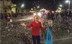  ?? PHOTO ?? A young girl in the crowd playfully attempts to eat the fake snow dispensed from the city of El Centro Community Services float during the 16th annual Parade of Lights held Friday night in Imperial. VINCENT OSUNA