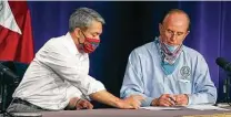  ?? Kin Man Hui / Staff photograph­er ?? Mayor Ron Nirenberg and Bexar County Judge Nelson Wolff look over informatio­n before a city-county coronaviru­s briefing.