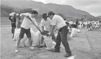  ??  ?? Nearly 200 employees of the Metropolit­an Cebu Water District help scrape off dried silt from the fourhectar­e Jaclupan infiltrati­on basin in Talisay City. An estimated 2,000 small sacks of silt were generated from the five-hour cleanup.