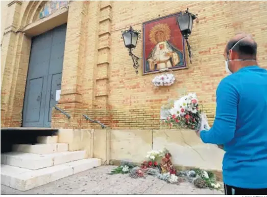  ?? ALBERTO DOMÍNGUEZ ?? Una persona se dirige hacia el azulejo de la Victoria para ofrecerle unas flores, ante una puerta cerrada y con la rampa de salida de los pasos montada.