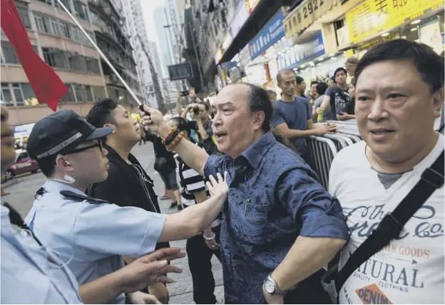  ?? PICTURE: ISAAC LAWRENCE/AFP/GETTY IMAGES ?? 0 A pro-beijing supporter waving a Chinese flag is held back by police as he tries to argue with pro-democracy activists yesterday