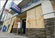  ?? MATT BORN — THE STAR-NEWS VIA AP, FILE ?? FILE- In this Tuesday file photo a man walks out of the boarded up Robert’s Grocery in Wrightsvil­le Beach, N.C., in preparatio­n for Hurricane Florence. Though it’s far from clear how much economic havoc Hurricane Florence will inflict on the southeaste­rn coast, from South Carolina through Virginia, the damage won’t be easily or quickly overcome. In those states, critically important industries like tourism and agricultur­e are sure to suffer. “These storms can be very disruptive to regional economies, and it takes time for them to recover,” said Ryan Sweet, an economist at Moody’s Analytics.