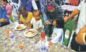  ??  ?? Fatimah feeds one of the homeless children, as her grandmothe­r and sibling look on.