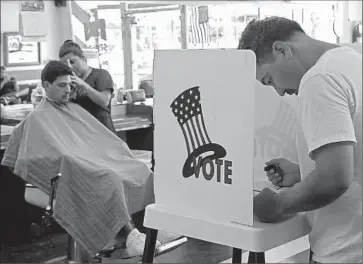 ?? Anne Cusack
Los Angeles Times ?? LASBIA BATISTA cuts Jose Bejarano’s hair on June 3, 2014, at Utah Barber Shop in Long Beach as Daniel Nakashima votes. While the Latino vote is big and growing, it’s nowhere near as big as it could be.